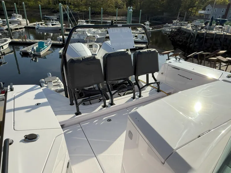 Slide: The Image of 2024 Axopar Cross Cabin boat with blue quilted seating, docked outdoors. - 7