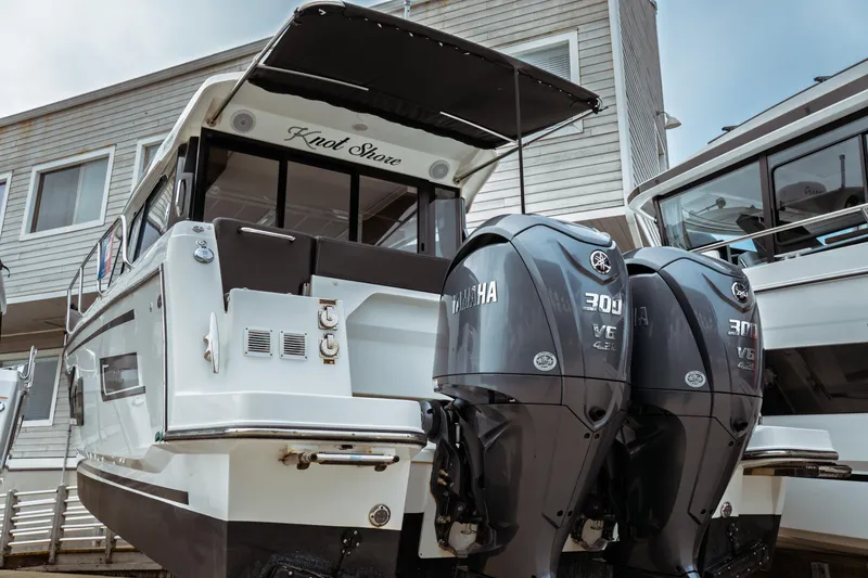 Slide: The Image of 2023 Jeanneau NC 1095 boat with twin Yamaha 300 engines, docked near a building. - 2