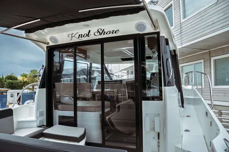 Slide: The Image of 2023 Jeanneau NC 1095 boat with sleek design and modern interior, docked near buildings. - 23