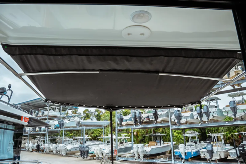 Slide: The Image of 2023 Jeanneau NC 1095 boat with retractable sunshade, surrounded by docked boats. - 24