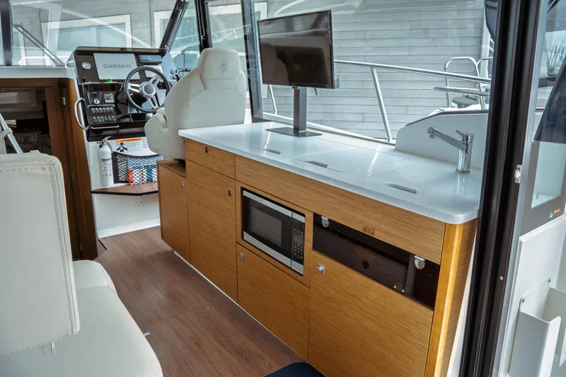 Slide: The Image of 2023 Jeanneau NC 1095 interior with helm, kitchenette, and modern amenities. - 36