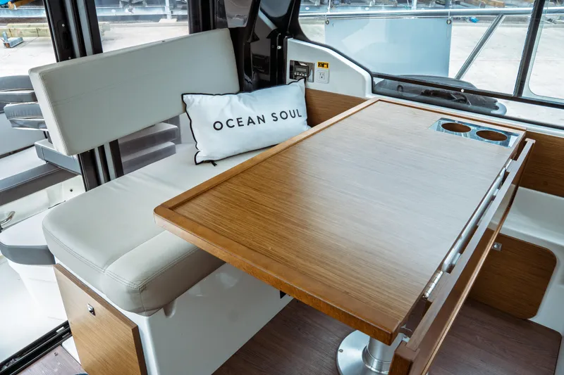 Slide: The Image of Interior of 2023 Jeanneau NC 1095 boat with wooden table and cushioned seating. - 38