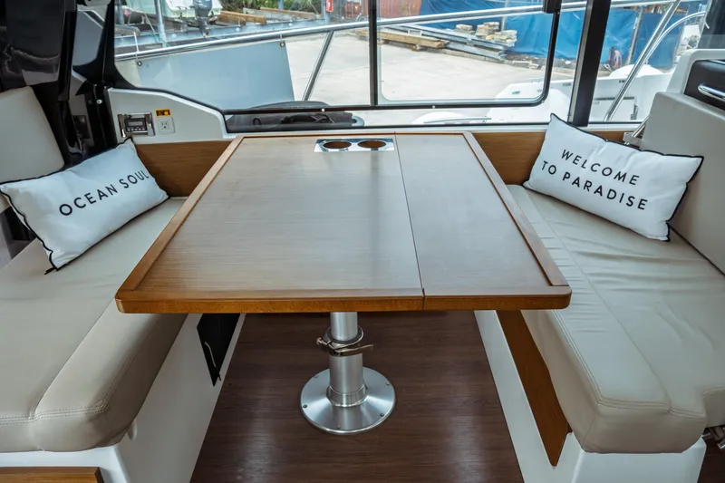 Slide: The Image of 2023 Jeanneau NC 1095 interior with wooden table and cushioned seating. - 40