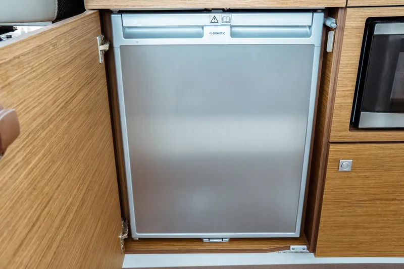 Slide: The Image of Built-in fridge on 2023 Jeanneau NC 1095 boat, featuring sleek wooden cabinetry. - 50