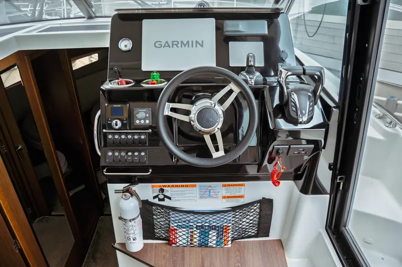 Slide: The Image of 2023 Jeanneau NC 1095 helm with Garmin navigation, steering wheel, and control panel. - 59