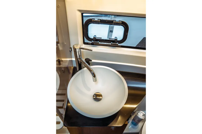 Slide: The Image of Modern bathroom sink in 2023 Jeanneau NC 1095 boat, featuring sleek faucet and porthole window. - 79