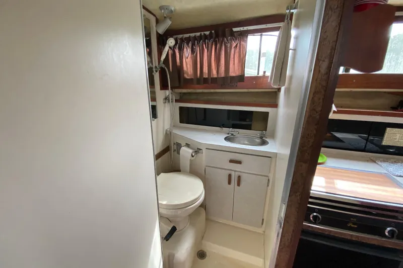 Slide: The Image of 1976 Slickcraft 28 Cruiser bathroom interior with sink, toilet, and window. - 11