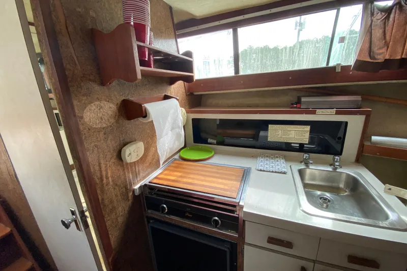 Slide: The Image of 1976 Slickcraft 28 Cruiser kitchen area with stove, sink, and storage shelves. - 7