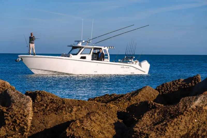 Slide: The Image of 2026 Solace 41 CS boat with anglers, fishing in open sea near rocky shore. - 3