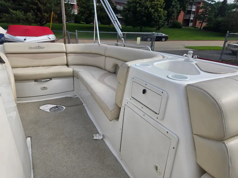 Slide: The Image of 2005 NauticStar 210 Sport Deck I/O interior with beige seating and storage compartments. - 4