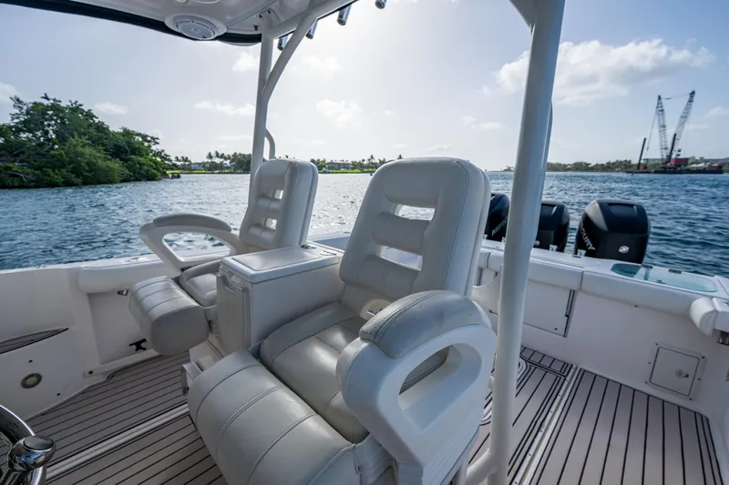 Slide: The Image of 2014 Everglades 350LX boat interior with white seating, overlooking water and distant cranes. - 14