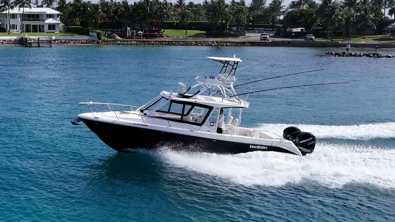 Slide: The Image of 2014 Everglades 350LX boat cruising on blue water near a tropical shoreline. - 2