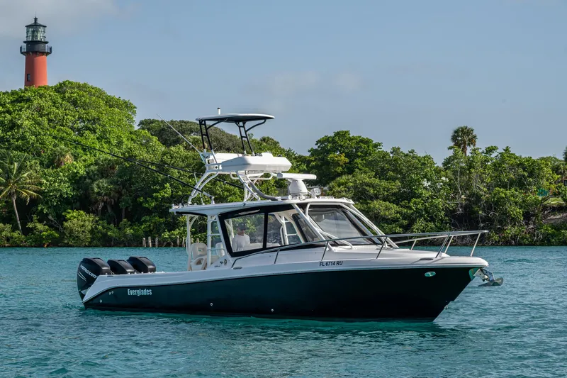 Slide: The Image of 2014 Everglades 350LX boat cruising near a lighthouse and lush greenery. - 26