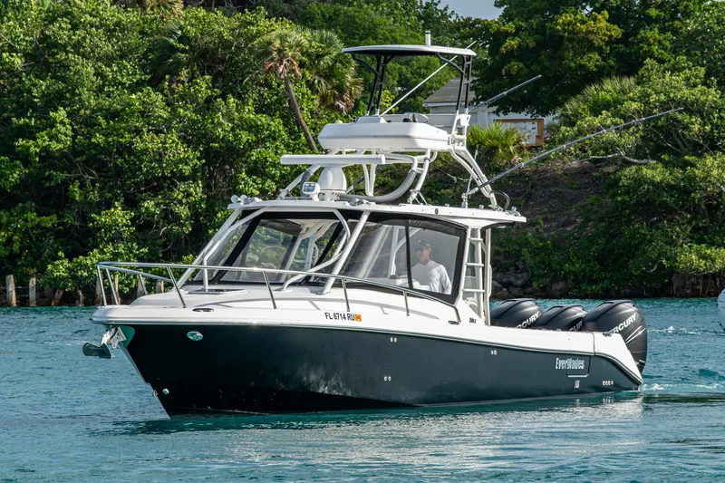 Slide: The Image of 2014 Everglades 350LX boat cruising on a scenic waterway with lush greenery. - 28