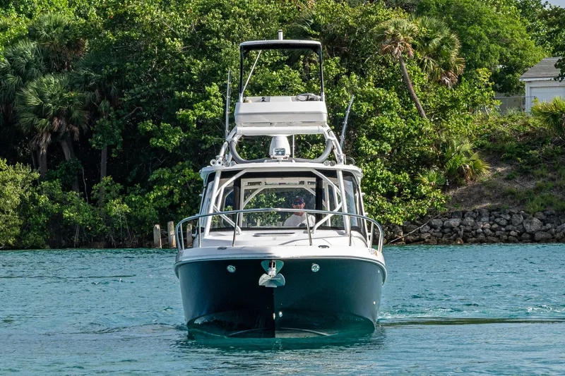Slide: The Image of 2014 Everglades 350LX boat cruising on a scenic waterway with lush greenery. - 4