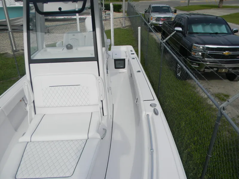 Slide: The Image of 2025 Sportsman Masters 247OE Bay Boat, white interior, parked beside a fence and vehicles. - 20
