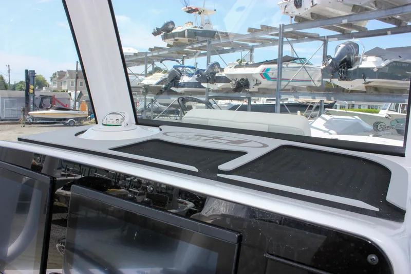 Slide: The Image of 2026 Sea Hunt Gamefish 27 dashboard with compass, marina background, and boat storage racks. - 41