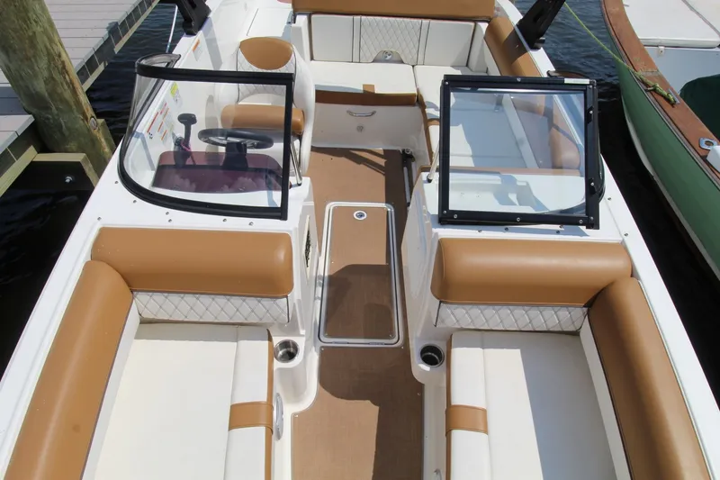 Slide: The Image of 2022 Bayliner DX2000 boat interior with tan and white seating, docked at marina. - 10