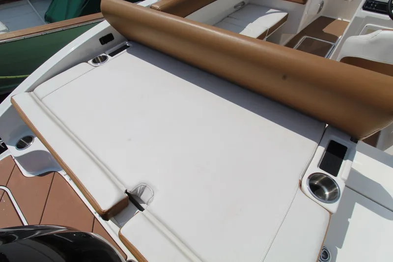 Slide: The Image of 2022 Bayliner DX2000 boat interior with white and brown seating, cup holders, and deck details. - 17