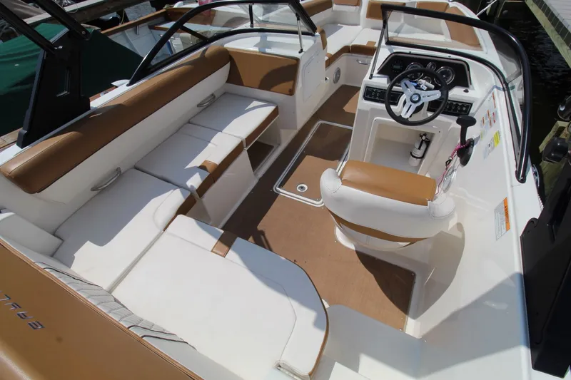 Slide: The Image of 2022 Bayliner DX2000 boat interior with tan and white seating, steering console, and modern design. - 18