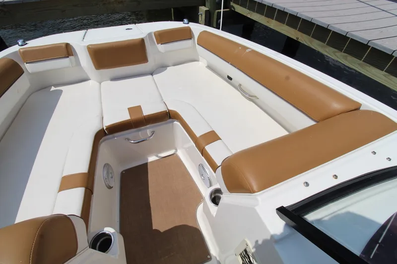 Slide: The Image of 2022 Bayliner DX2000 boat interior with tan and white seating, dockside view. - 22