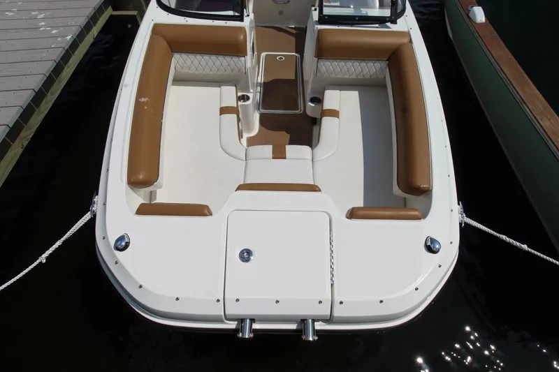 Slide: The Image of 2022 Bayliner DX2000 boat with tan seating, docked on calm water. - 9