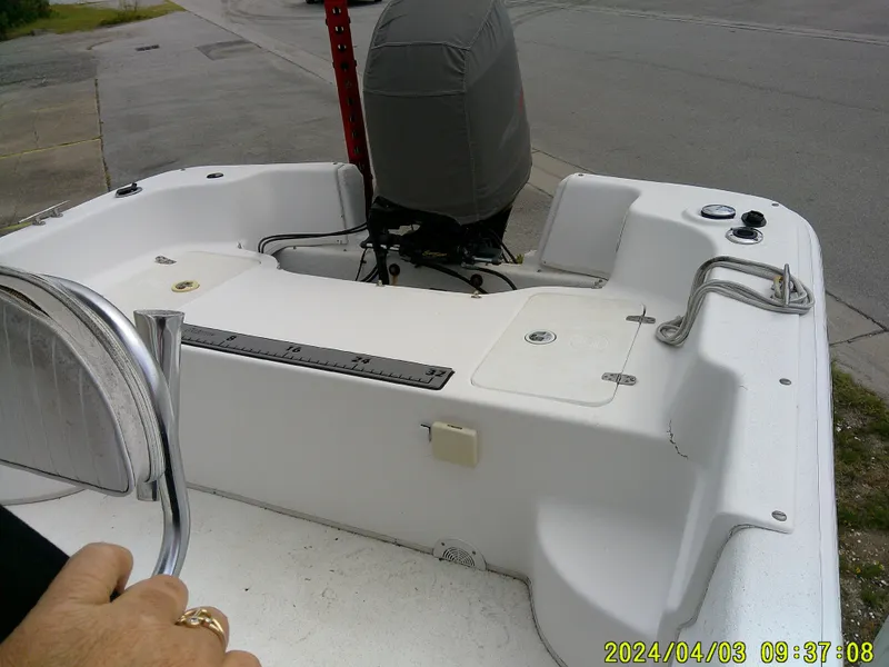 Slide: The Image of 2010 Carolina Skiff 238 DLV boat interior with covered outboard motor, docked on a street. - 15
