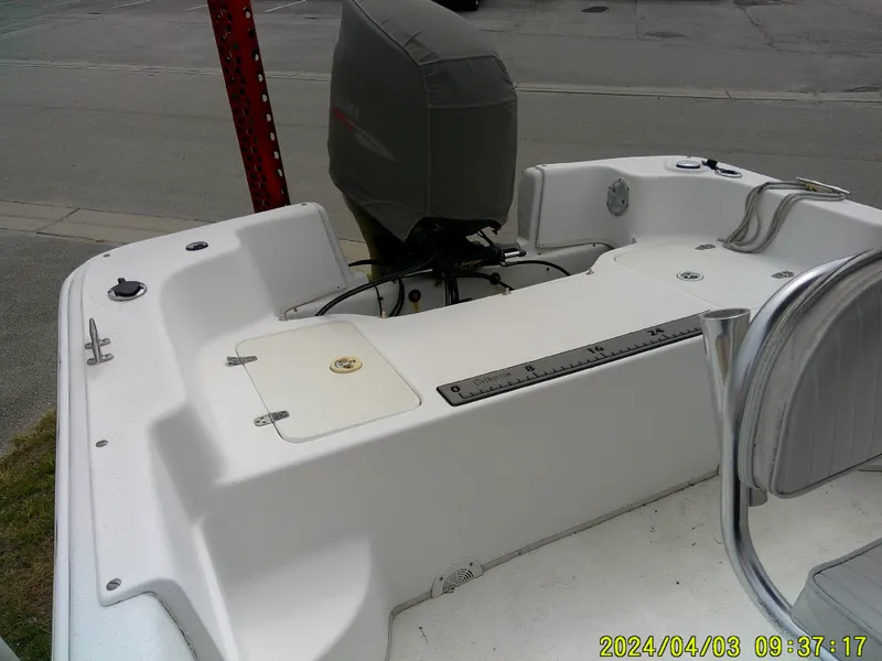 Slide: The Image of 2010 Carolina Skiff 238 DLV boat with covered outboard motor, docked on a street. - 16