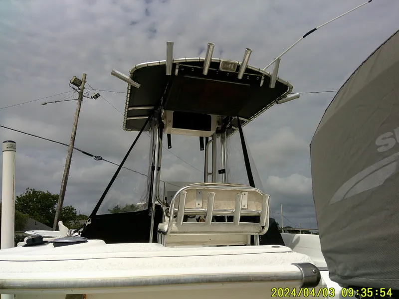 Slide: The Image of 2010 Carolina Skiff 238 DLV boat with T-top and fishing rod holders under cloudy sky. - 6