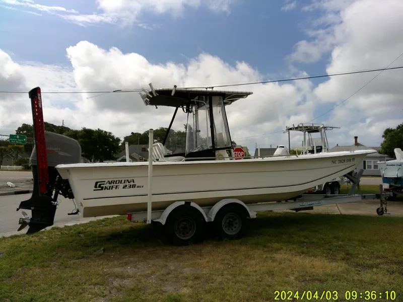 Slide: The Image of 2010 Carolina Skiff 238 DLV boat on trailer, parked outdoors under cloudy sky. - 8