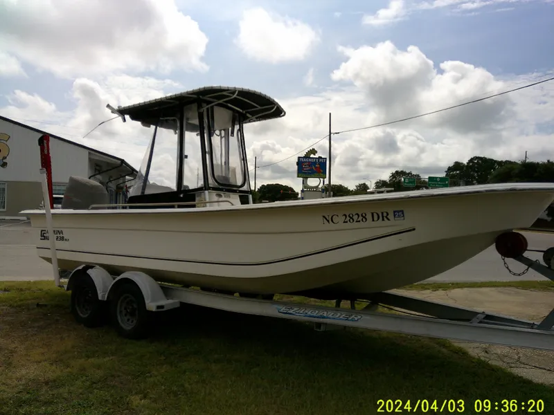 Slide: The Image of 2010 Carolina Skiff 238 DLV boat on trailer, parked outdoors under cloudy sky. - 9