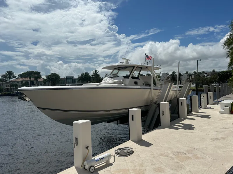 Slide: The Image of Pursuit 408S 2018 boat docked by waterfront under cloudy sky. - 0