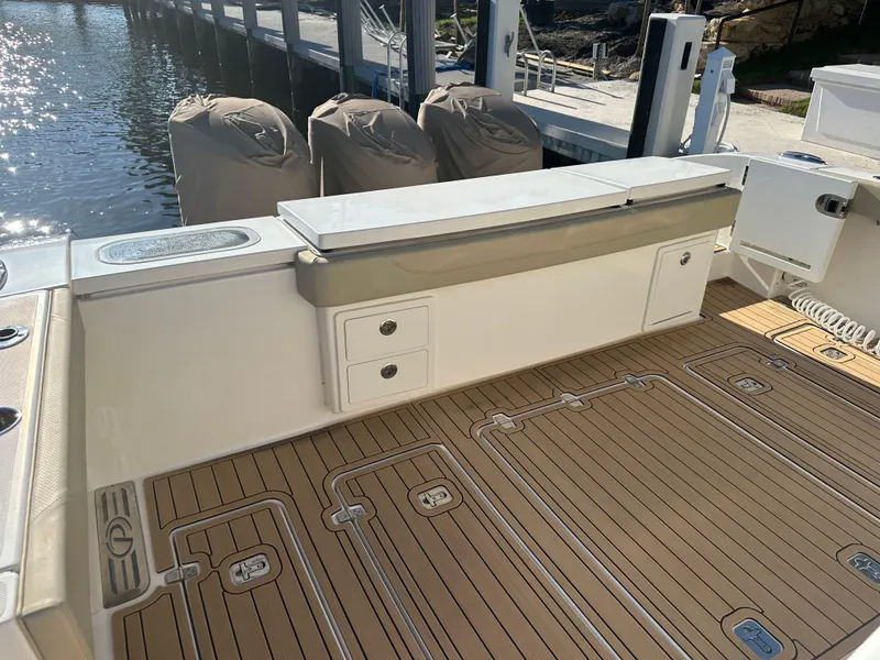 Slide: The Image of 2018 Pursuit 408S boat deck with teak flooring and covered engines at dock. - 1