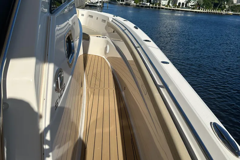 Slide: The Image of 2018 Pursuit 408S boat deck with wood finish, docked by calm waters. - 25
