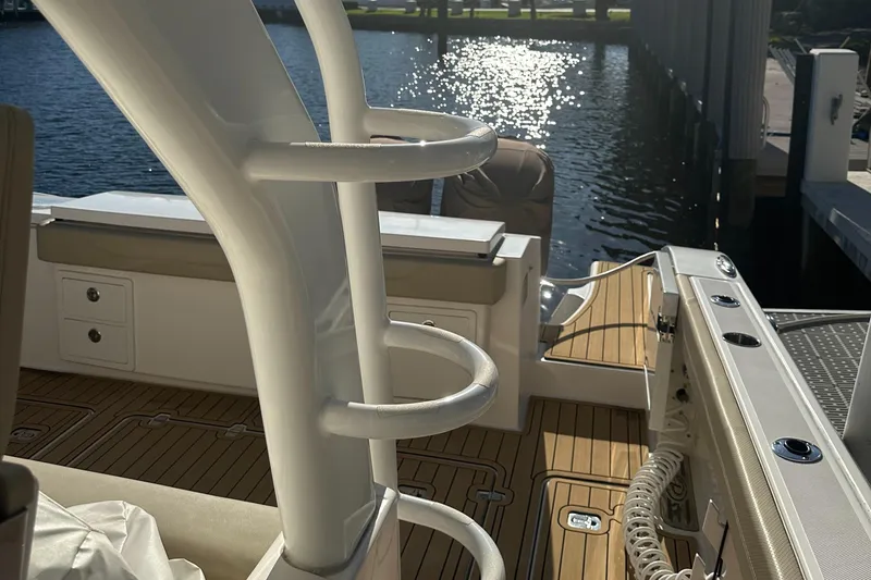 Slide: The Image of 2018 Pursuit 408S boat interior with teak flooring and rod holders by the water. - 27