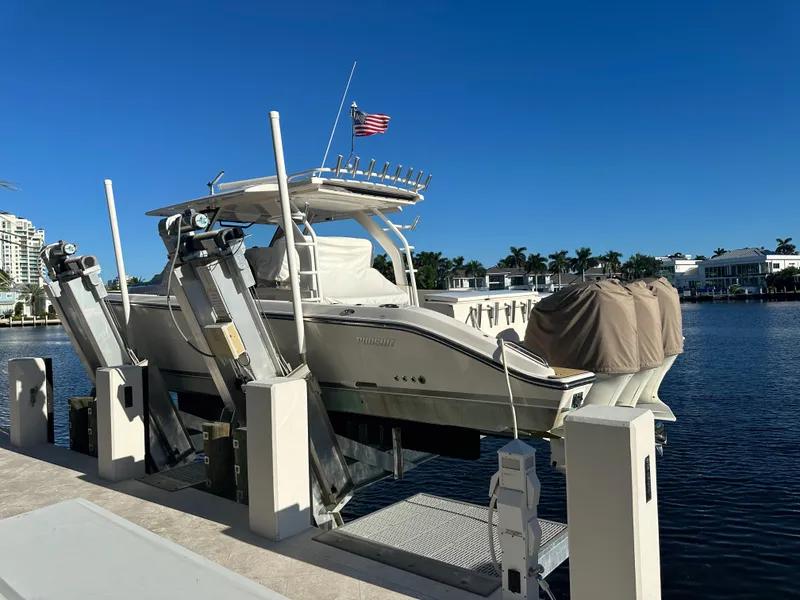 Slide: The Image of 2018 Pursuit 408S boat docked on lift, American flag, waterfront homes in background. - 29