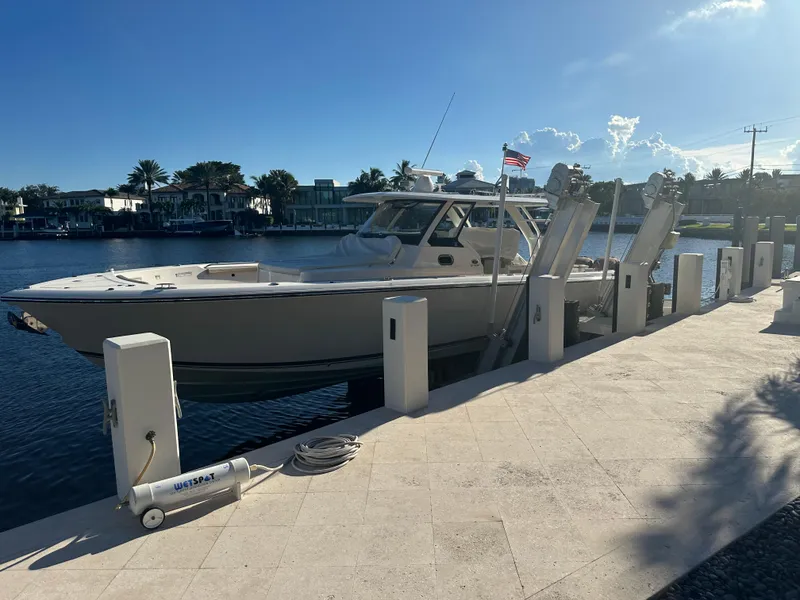 Slide: The Image of 2018 Pursuit 408S boat docked by waterfront homes under clear sky. - 30