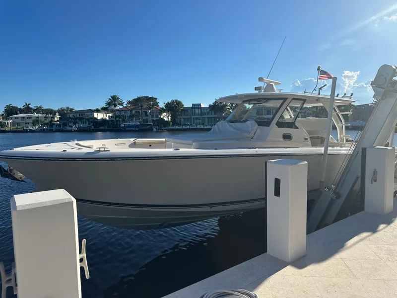 Slide: The Image of 2018 Pursuit 408S boat docked by waterfront homes under clear blue sky. - 5