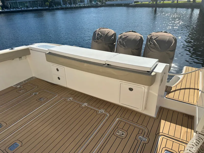 Slide: The Image of 2018 Pursuit 408S boat deck with covered engines, docked by the water. - 7