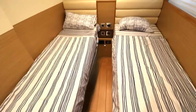 Slide: The Image of Twin beds with striped bedding in a 2027 Selene 64 yacht cabin. - 8