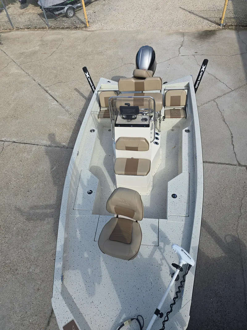 Slide: The Image of 2020 Xpress H20B boat with beige seating and steering console, parked on concrete. - 13