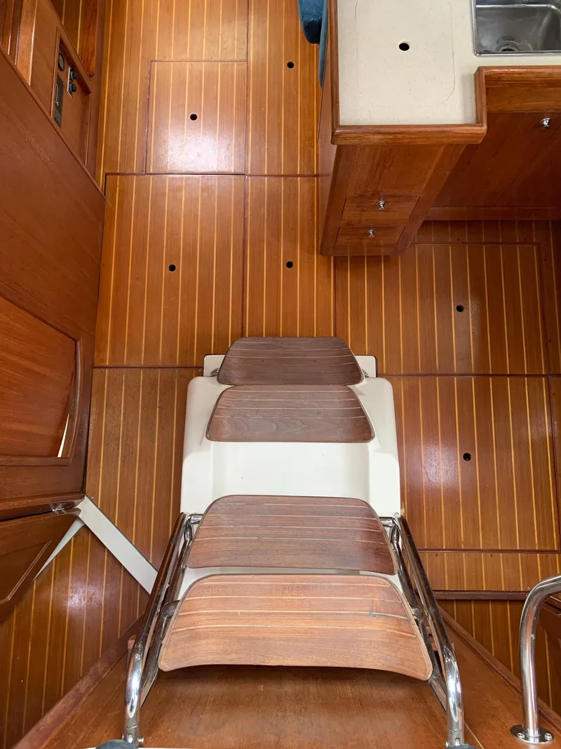 Slide: The Image of Interior of a 2002 Hunter 410 sailboat with wooden flooring and compact kitchen area. - 19