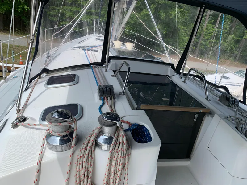 Slide: The Image of 2002 Hunter 410 sailboat deck with winches and ropes, surrounded by lush greenery. - 23