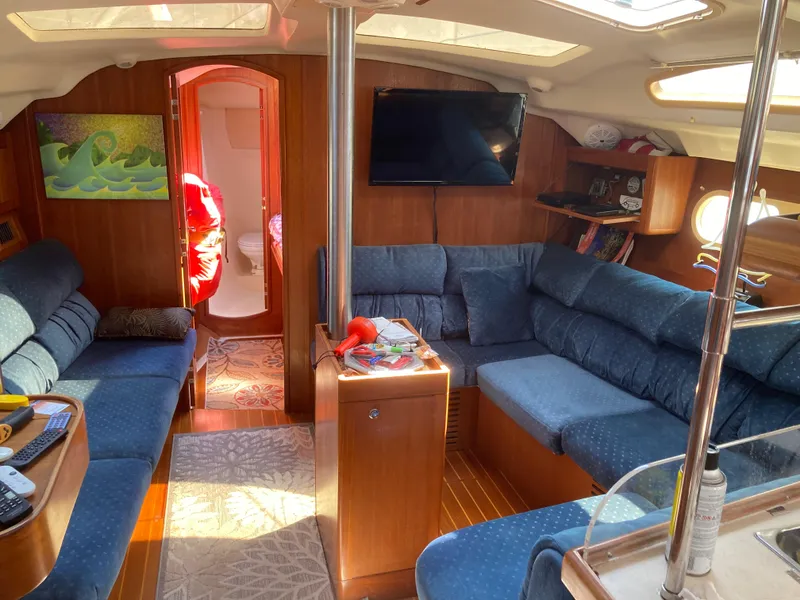 Slide: The Image of Interior of a 2002 Hunter 410 sailboat with blue seating and wooden accents. - 32