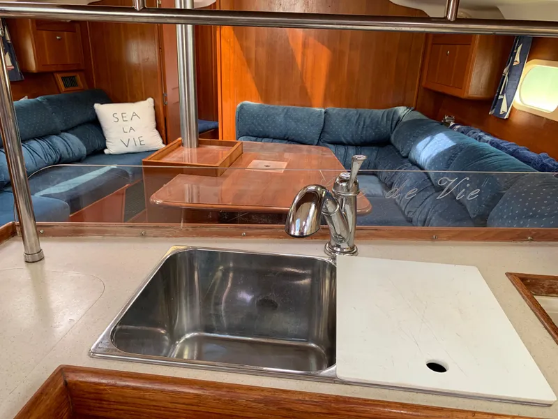 Slide: The Image of Interior of 2002 Hunter 410 yacht with sink, blue seating, and "Sea La Vie" pillow. - 8
