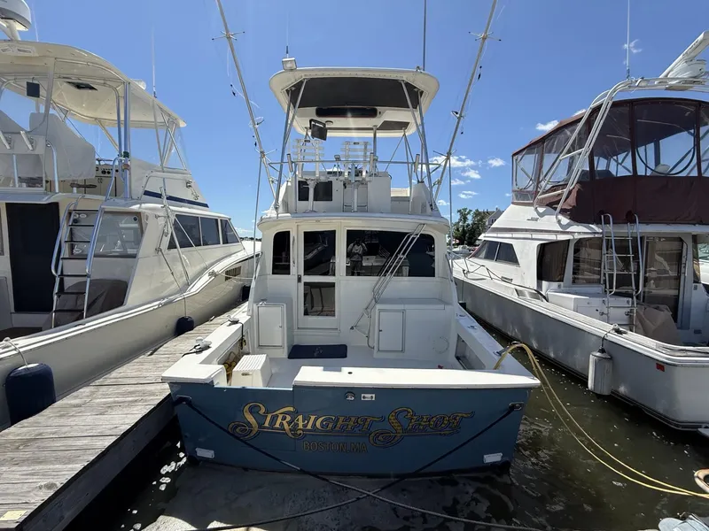 Slide: The Image of 1988 Ocean Yachts 35 Flybridge docked between boats under clear blue sky. - 2
