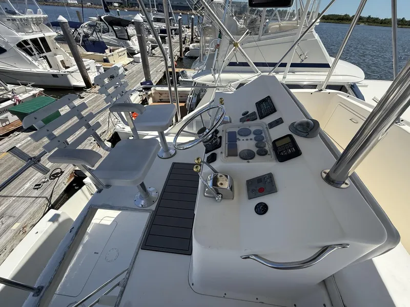 Slide: The Image of 1988 Ocean Yachts 35 Flybridge helm with controls and seating at marina. - 6