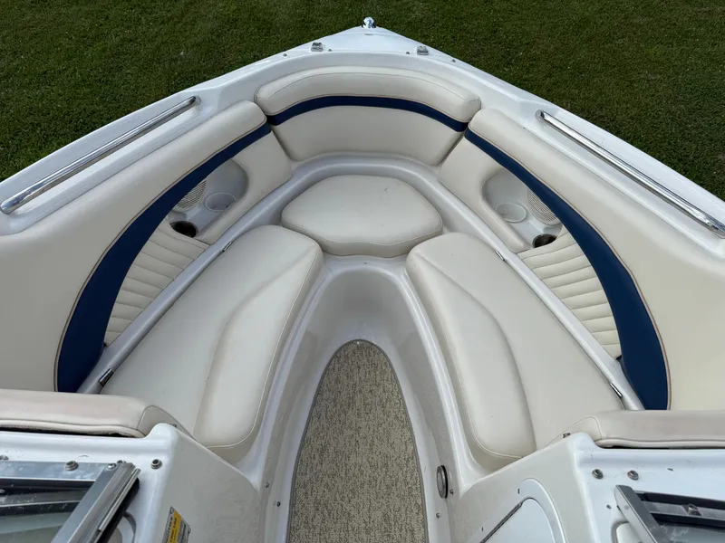Slide: The Image of 1999 Chris-Craft 200 Bowrider SS interior with white and blue seating on grass. - 11