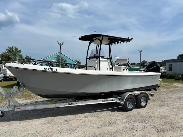 The Image of 2022 May-Craft 2300 CCX boat on trailer, parked outdoors under a cloudy sky. - 1