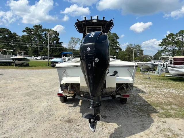 Slide: The Image of 2022 May-Craft 2300 CCX boat with outboard motor, parked on gravel lot under blue sky. - 6